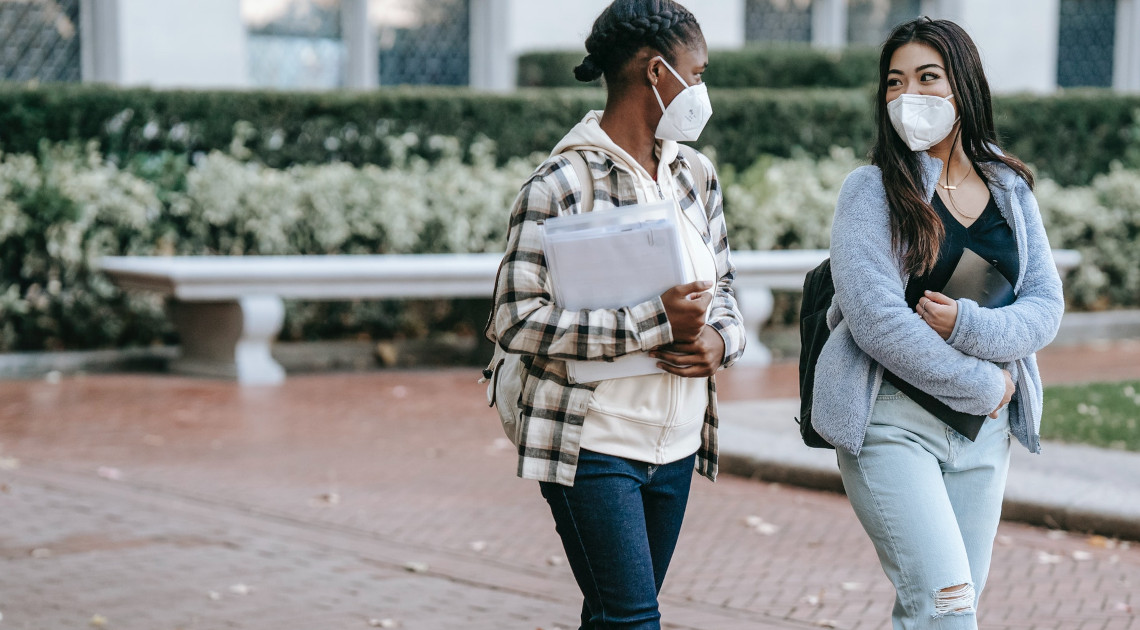 Zwei junge Frauen mit Mund-Nase-Bedeckung im Gespräch: Auch an Bayerns Hochschulen ist bestmöglicher Gesundheitsschutz weiterhin die Maxime